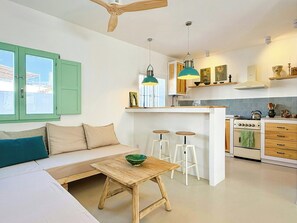 A modern kitchen with white cabinets, a wooden island, and a dining area with a wooden table and stools. - Charming Artisanal Home in Vejer de la Frontera (Vejer de la Frontera)