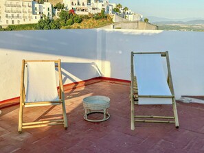 Deux chevalets sur une terrasse en toit-terrasse, offrant une vue sur des bâtiments blancs et un paysage lointain.
