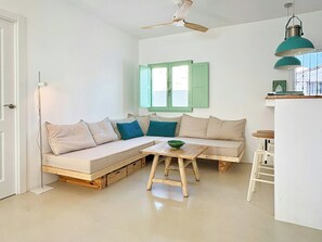 Ein gemütlicher Wohnbereich mit einer Couch, einem kleinen Tisch und einem Deckenventilator.