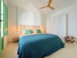 A bedroom with a bed, a wardrobe, a ceiling fan, and a small table. - Charming Artisanal Home in Vejer de la Frontera (Vejer de la Frontera)