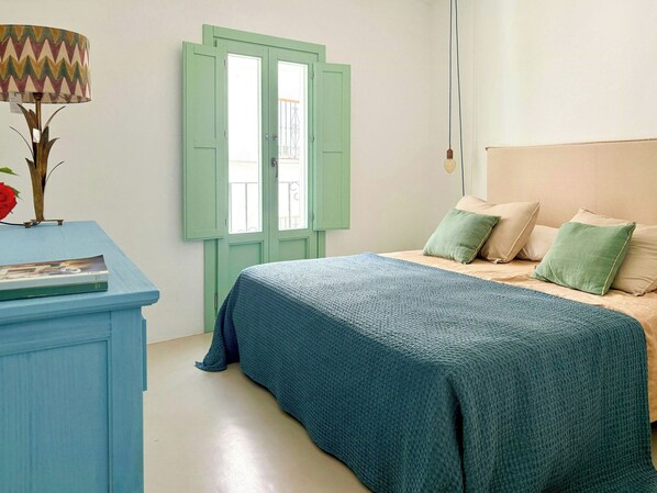 Ein Schlafzimmer mit einem Bett, einem Schminktisch und einem Fenster mit Fensterläden.
