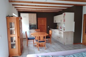 A compact kitchen with wooden cabinets, a dining table with chairs, and a built-in oven. - Dog holiday home Derber (Mohrweiler)