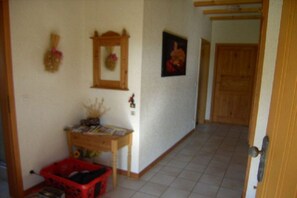 A hallway with a wooden door, a small table with items, and a red basket. - Dog holiday home Derber (Mohrweiler)