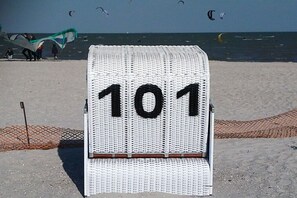 Une plage avec une chaise blanche portant le numéro « 101 » et une zone délimitée par un filet.