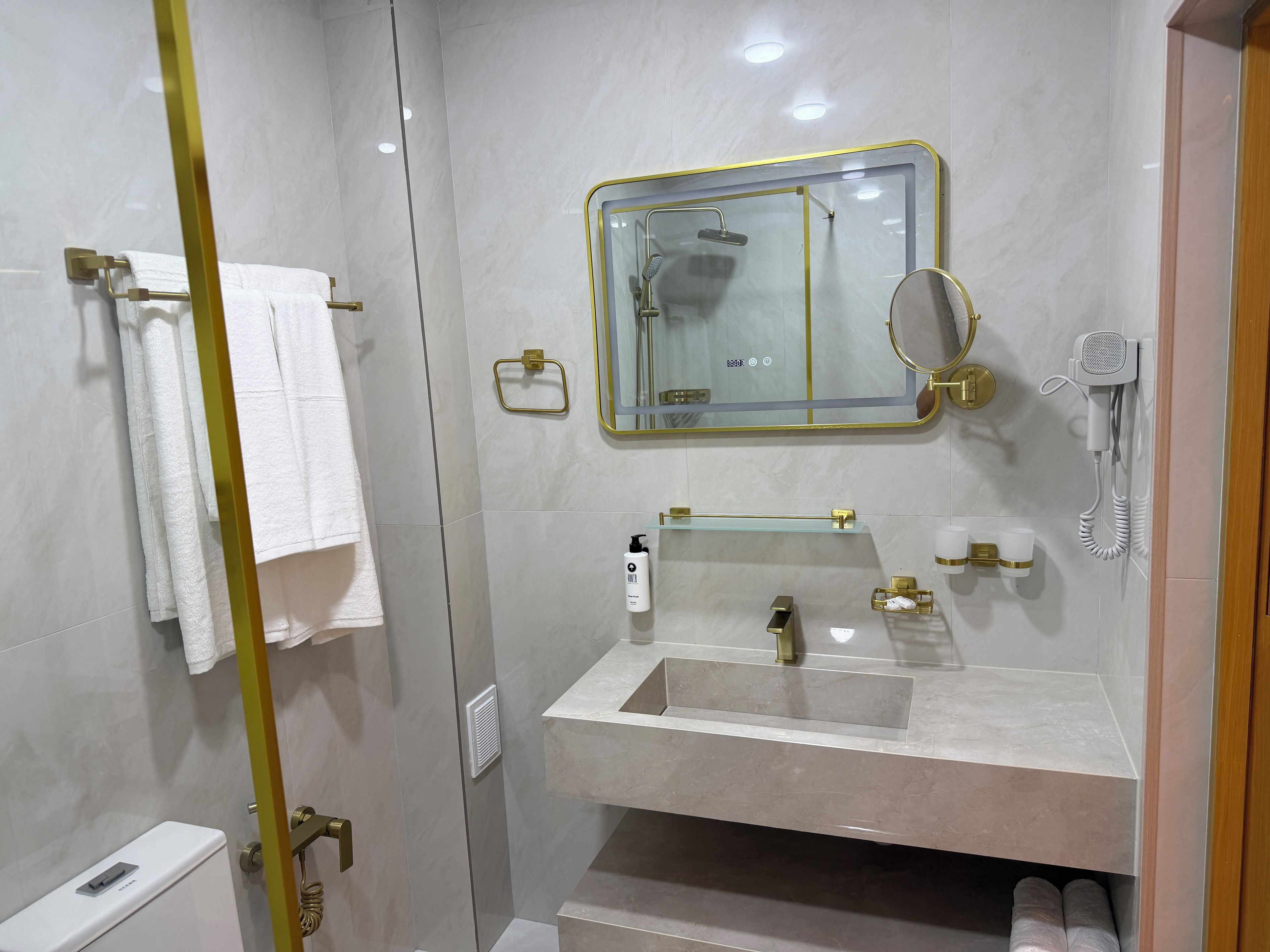 Ein modernes Badezimmer mit einer Duschkabine, einem Waschtisch mit Spiegel und einer Toilette.