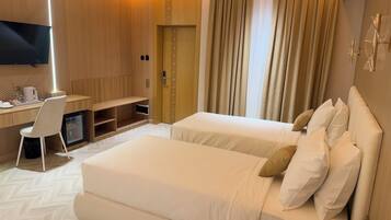 A hotel room with a bed, a desk, a chair, a television, and a minibar.