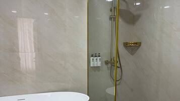 A modern bathroom with a freestanding bathtub, a glass-enclosed shower, and a gold-framed mirror.