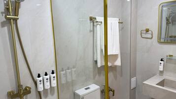 A modern bathroom with a glass-enclosed shower, a white sink, and a mirror with a gold frame.