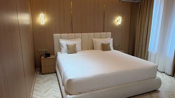 Ein modernes Schlafzimmer mit einem großen Bett, Holzwandverkleidungen und einem Fischgrätparkett.