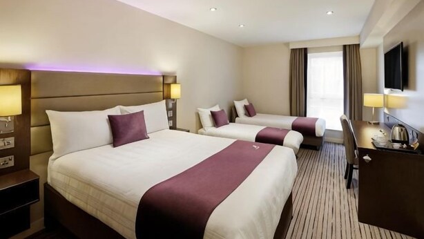 Quarto de hotel com duas camas, uma escrivaninha e televisão.
