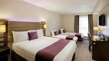 A hotel room with two beds, a desk, and a TV.