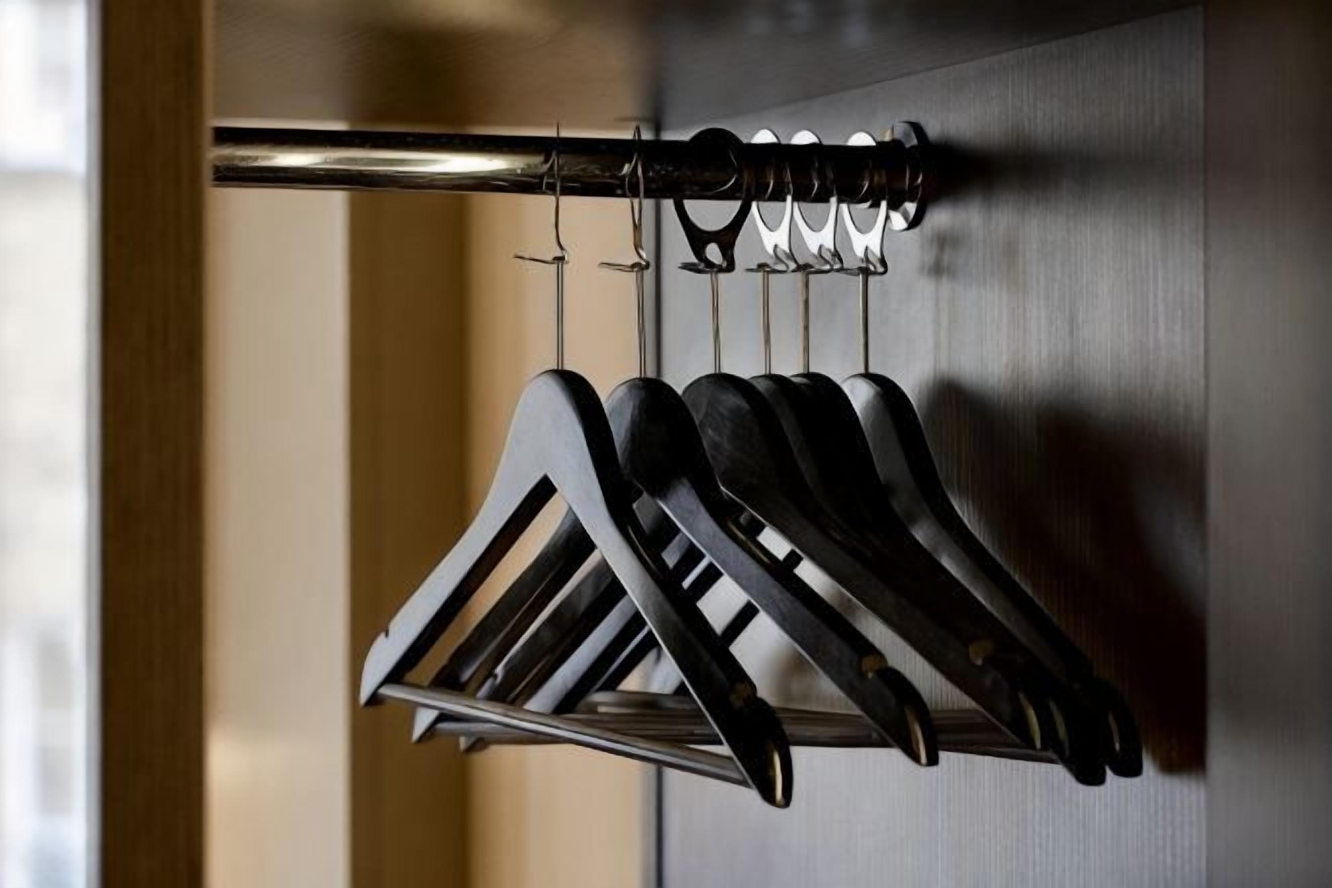 A metal rack with multiple hangers holding items, likely clothing, against a wall.