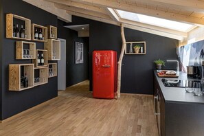 Eine moderne Küche mit einem roten Kühlschrank, Weinheraus und einem Oberlicht.