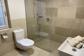 A bathroom with a toilet, a glass-enclosed shower, and a sink with a towel. - Guesthouse of the Brombeerhof (Kampen)