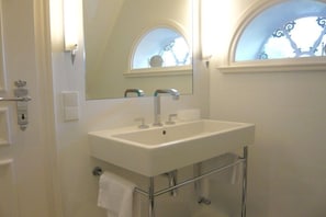 Une salle de bain avec un lavabo blanc, un robinet chromé et un miroir au-dessus.