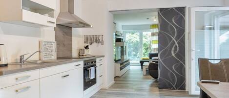 A modern kitchen with white cabinetry, a built-in oven, and a stainless steel range hood.