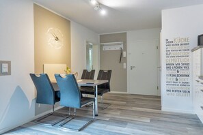 A modern dining area with a table and chairs, a wall clock, and a menu board. - Holiday apartment with 1 bedroom (Bad Zwischenahn)