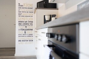 Une cuisine moderne dotée d’un four encastré et d’une machine à café posée sur le plan de travail.