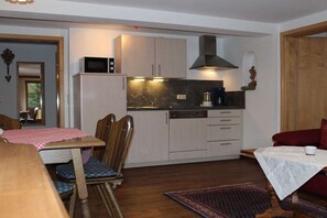 A compact kitchen with a microwave, stove, and sink, adjacent to a dining area with a table and chairs. - at the country house Heel (Schwangau)