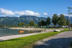 A lakeside view with a grassy area, a boat, and mountains in the background. - at the country house Heel (Schwangau)