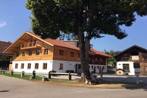 En traditionel træbygning med balkon, hvid facade og rødt tag.