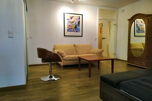 Een woonkamer met een bank, een salontafel, een stoel en een spiegel.
