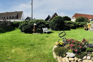 A residential area with a well-maintained lawn, a white bench, and a garden with flowers and shrubs. - Holiday apartment with 2 bedrooms (Westerland\/Sylt)