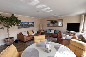 A living room with a sofa set, a coffee table, a television, and a potted plant. - Holiday apartment with 2 bedrooms (Westerland\/Sylt)