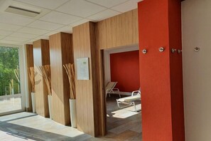 Un passadís amb panells de fusta, una paret vermella i una porta que dona a una habitació amb un llit.