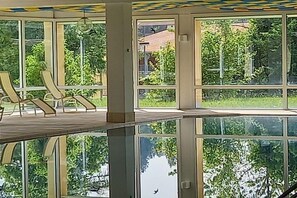 Ein Zimmer mit großen Fenstern, einem Holztisch und Stühlen.