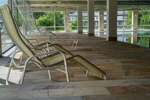 Ein überdachter Außenbereich mit Liegestühlen und gefliestem Boden.