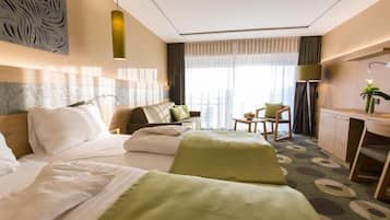 A hotel room with a bed, a sofa, a desk, and a chair.