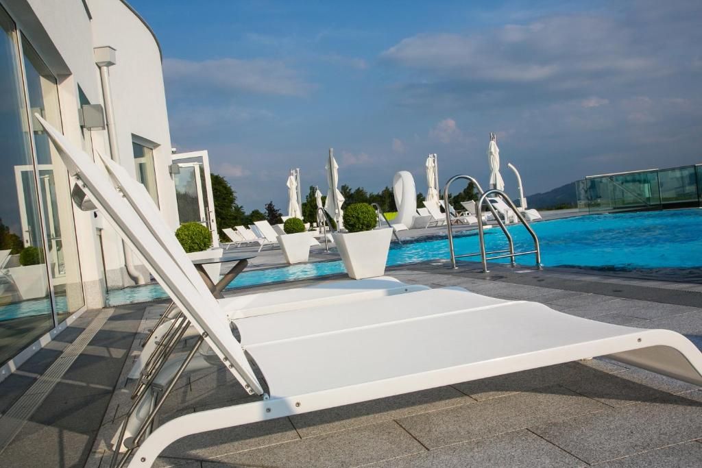 A poolside area with sun loungers, a glass balustrade, and a clear sky.