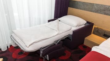 Una cama individual con cabecera, una mesita de noche y un mueble con cajones.