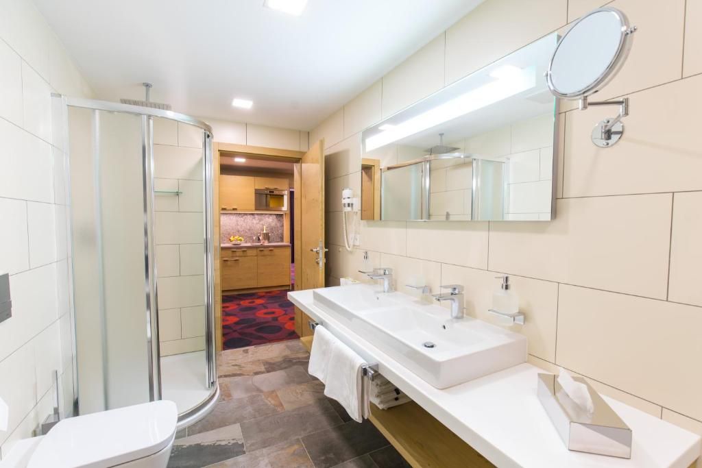 Een moderne badkamer met een douchecabine van glas, een grote spiegel en een wastafelmeubel met dubbele wastafel.
