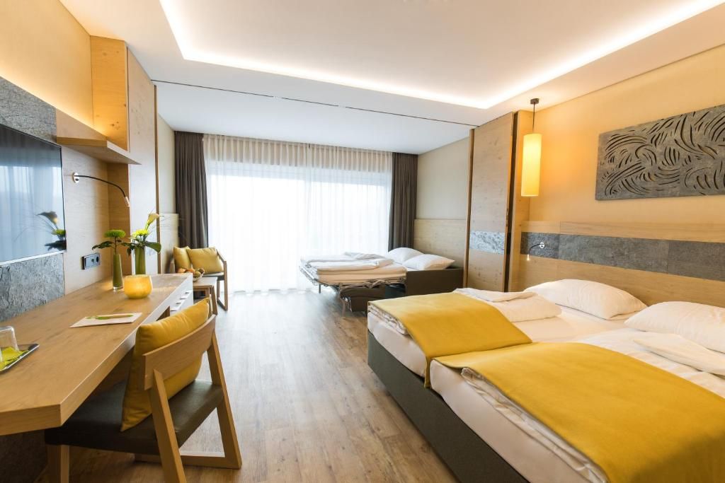 Een hotelkamer met een bed, nachtkastje en bureau met stoel.