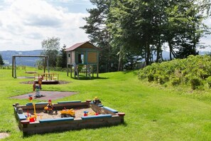 A playground with a sandbox, swings, and a small wooden structure.
