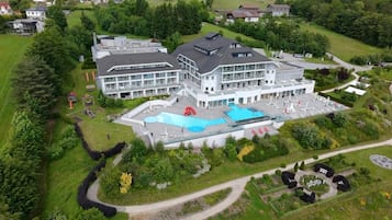 A large building with multiple floors, a swimming pool, and a landscaped area with pathways.