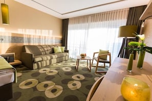 A hotel room with a sofa, a small table with a bowl of fruit, a chair, and a lamp. - Aigo welcome Family  (Aigen-Schlägl)