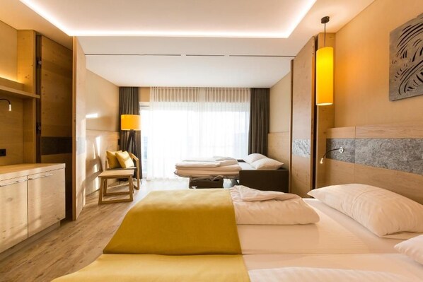 A hotel room with a bed, a desk, a chair, and a window with curtains.