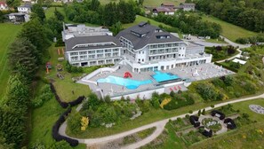 Un edificio grande con varios pisos, piscina y zonas ajardinadas con senderos.