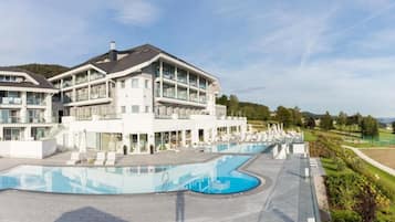 A multi-story hotel with a swimming pool, outdoor seating, and a landscaped garden.