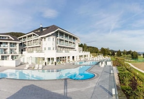 A multi-story hotel with a swimming pool, outdoor seating, and a landscaped garden. - Aigo welcome Family  (Aigen-Schlägl)