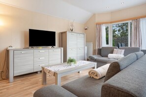 Ett modernt vardagsrum med en platt-TV, en soffa, ett soffbord och ett skåp.