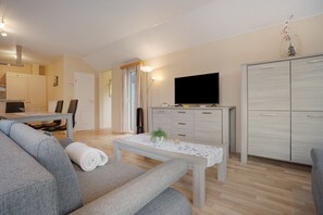A modern living room with a sofa, a coffee table, a flat-screen TV, and a cabinet. - Bungalow 'Haus S 41 Paulchen' with Private Terrace, Private Garden and Wi-Fi (Röbel/Müritz)