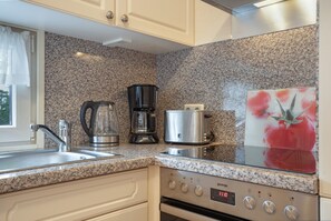 A kitchen with granite countertops, a coffee maker, a toaster, and a digital clock. - Bungalow 'Haus S 41 Paulchen' with Private Terrace, Private Garden and Wi-Fi (Röbel/Müritz)
