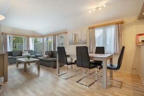 Ett modernt vardagsrum med en soffa, ett soffbord och en matplats med stolar.