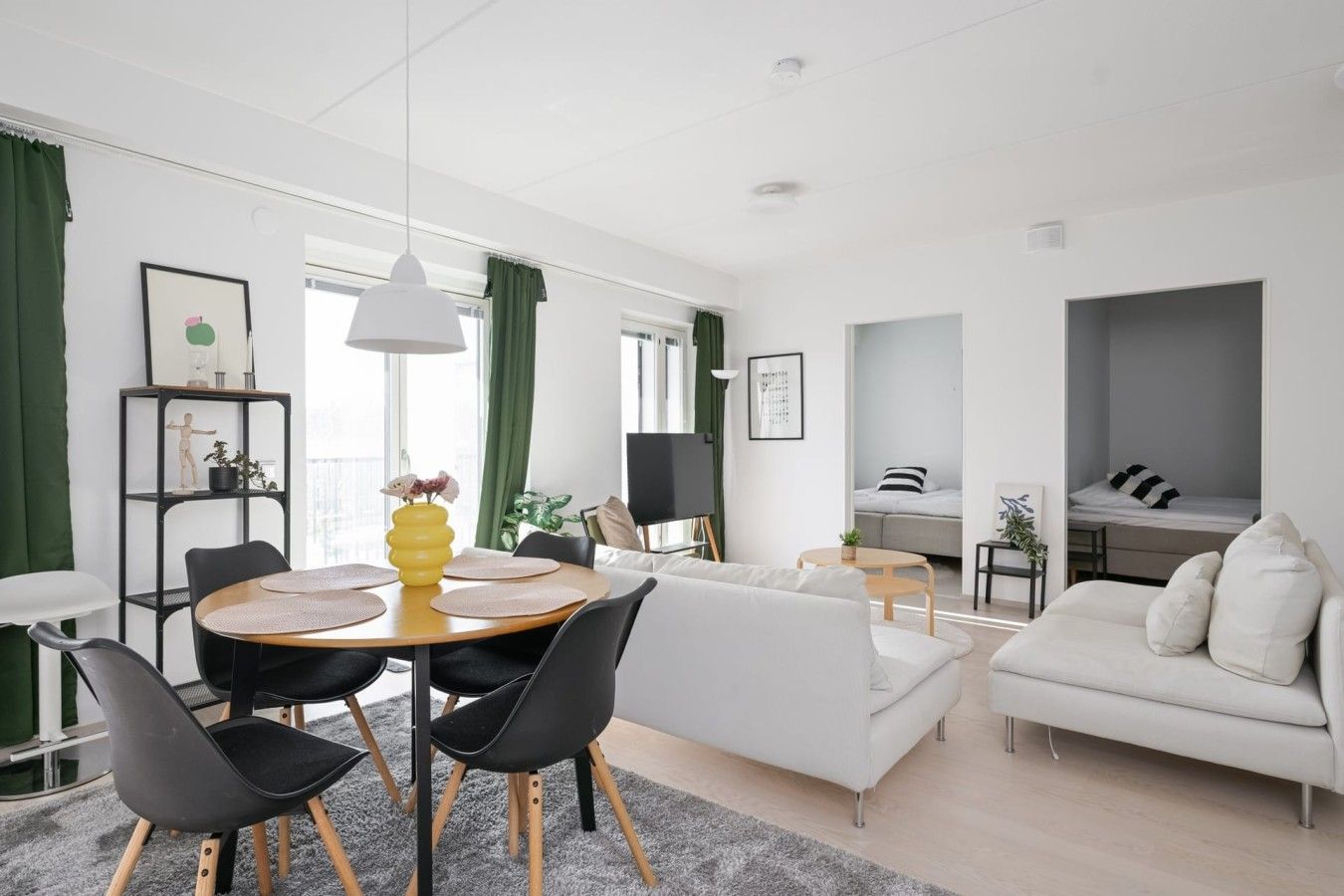 Un salon moderne comprenant un coin repas, un canapé, un lit et une petite table avec une lampe.