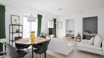 Un salon moderne comprenant un coin repas, un canapé, un lit et une petite table avec une lampe.