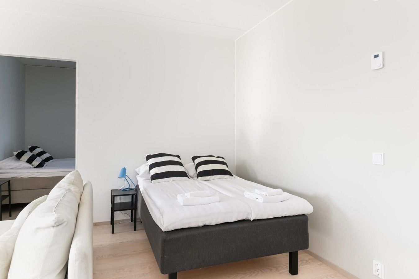 A modern bedroom with a bed, bedside table, and a desk area.
